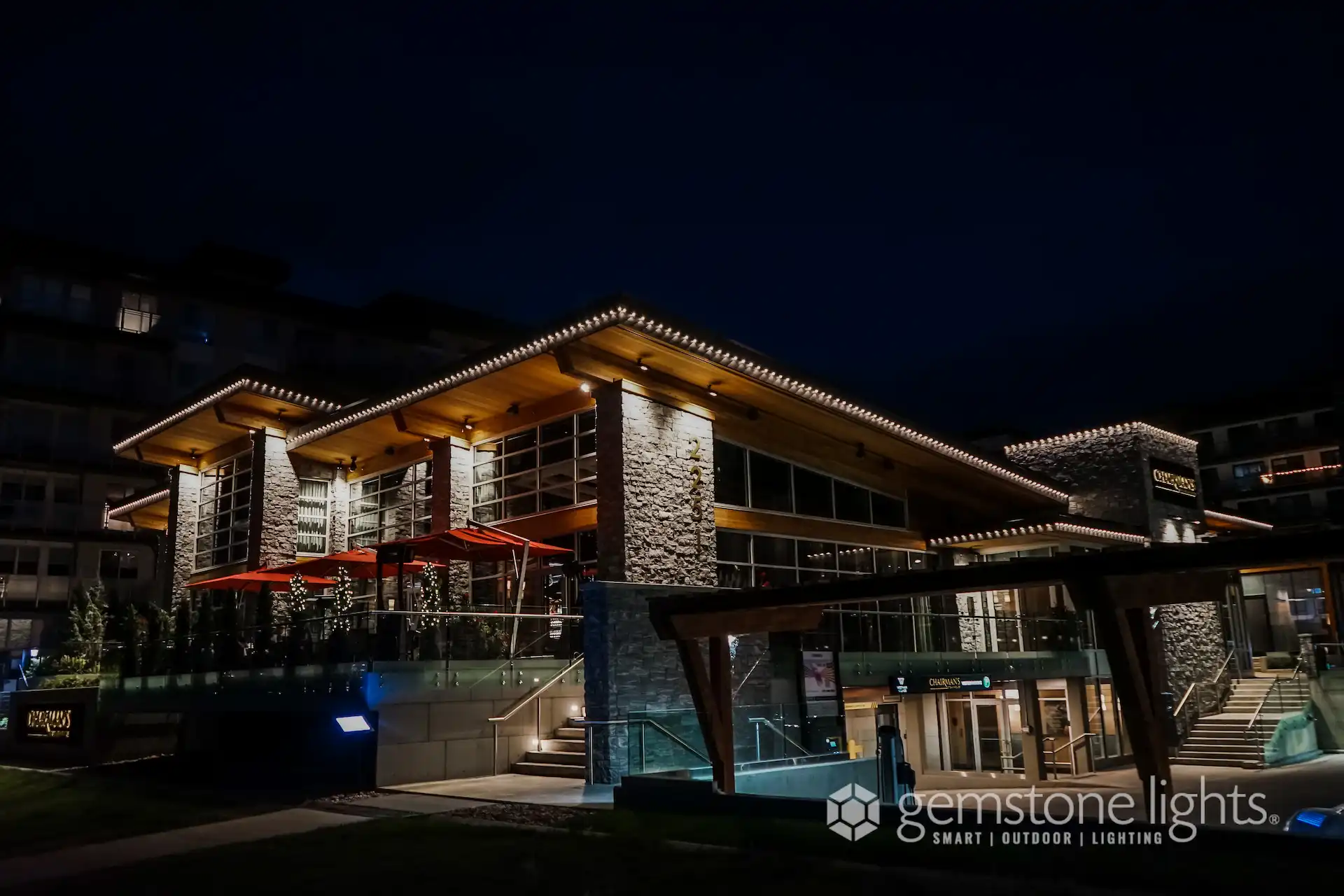 A beautifully lit modern building showcases a blend of stone and wood architecture at night