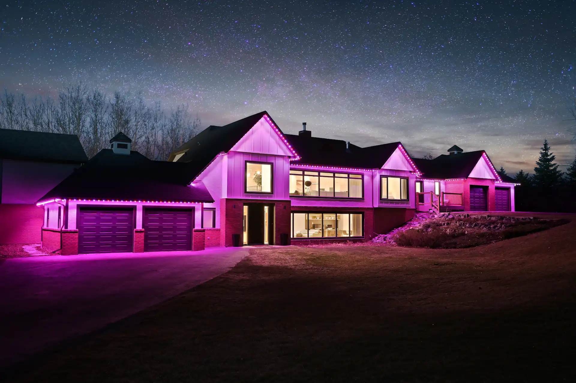 A modern house is illuminated with vibrant pink lights against a starry night sky