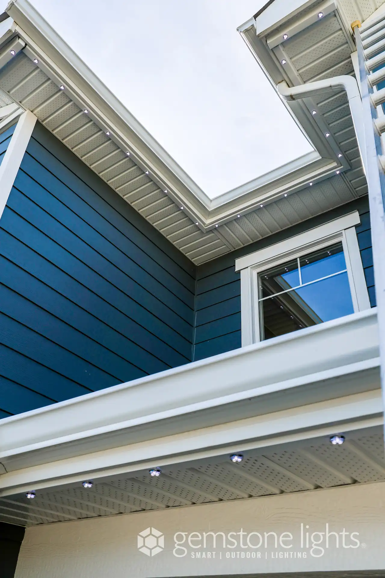 A blue house with angular architecture features LED lights along the eaves