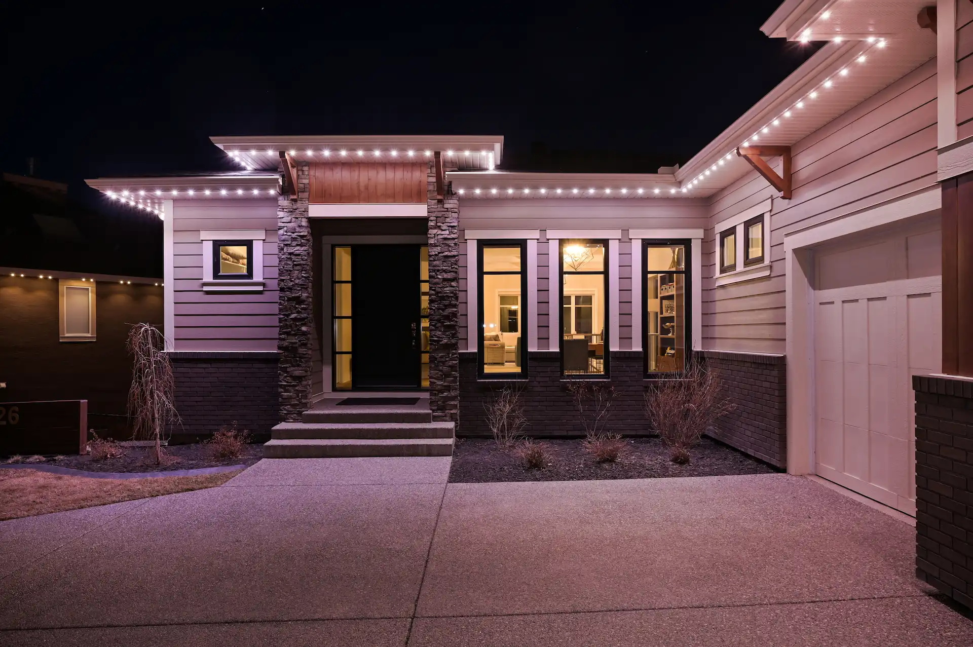 A beautifully lit modern home welcomes visitors with warm lights at night
