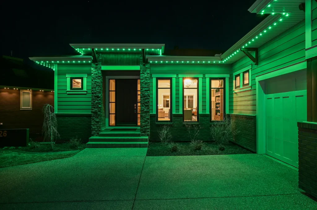 The house is illuminated with vibrant green lights along its structure at night