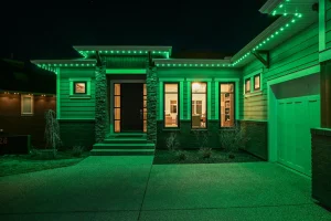 The house is illuminated with vibrant green lights along its structure at night