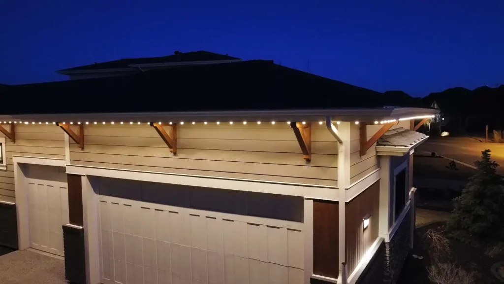 Twinkling lights adorn a home's eaves against a twilight sky