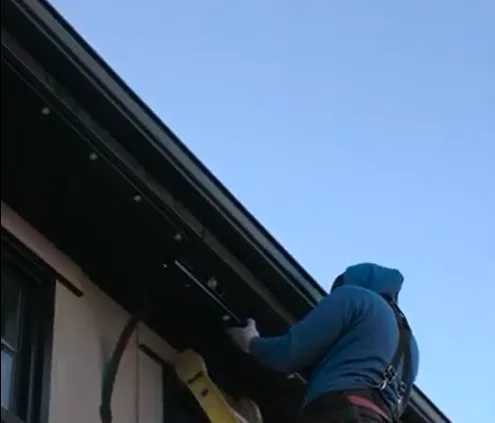 A person climbs a ladder to work on a house's roof